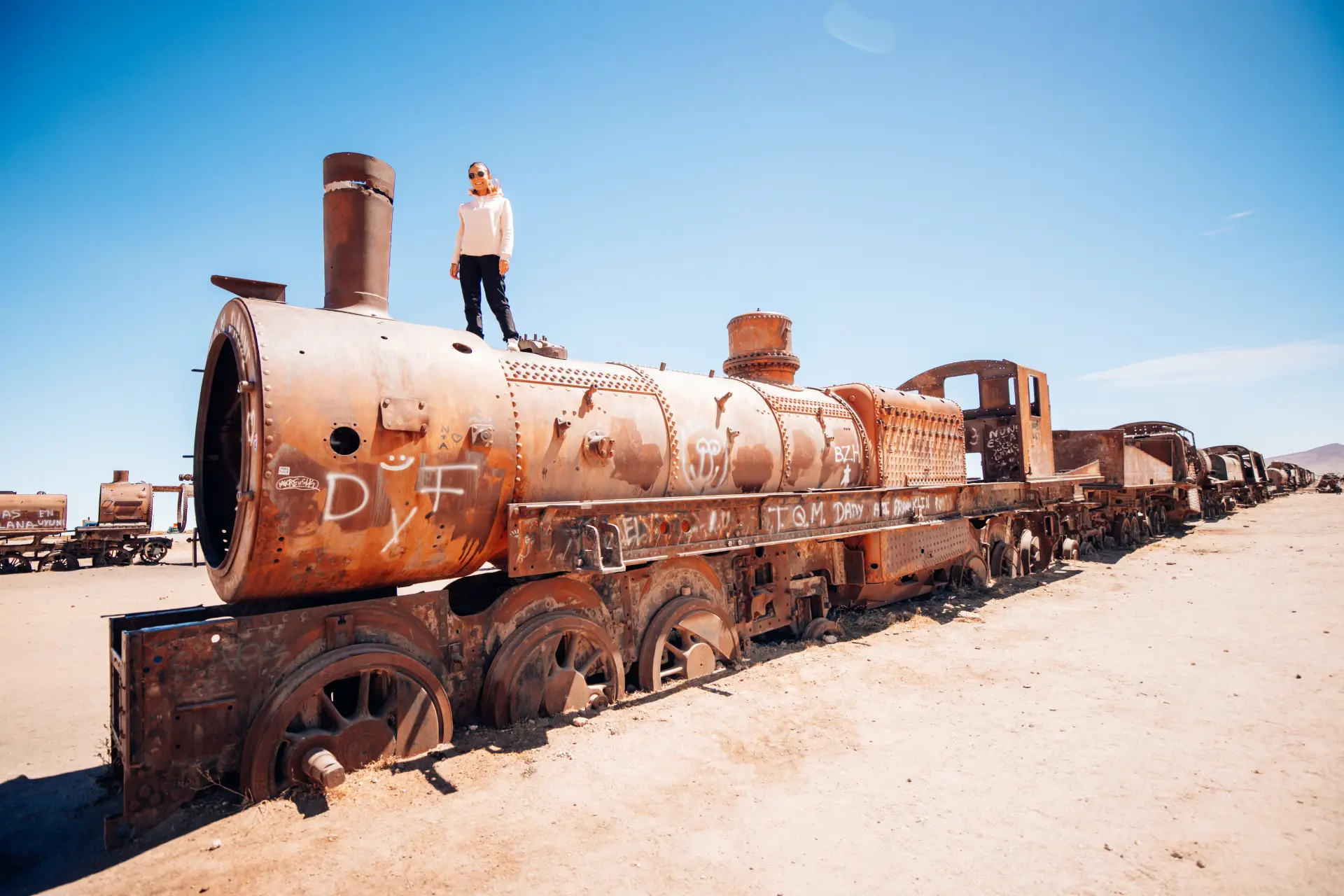 Maria in piedi su una locomotiva arrugginita nel cimitero dei treni di Uyuni