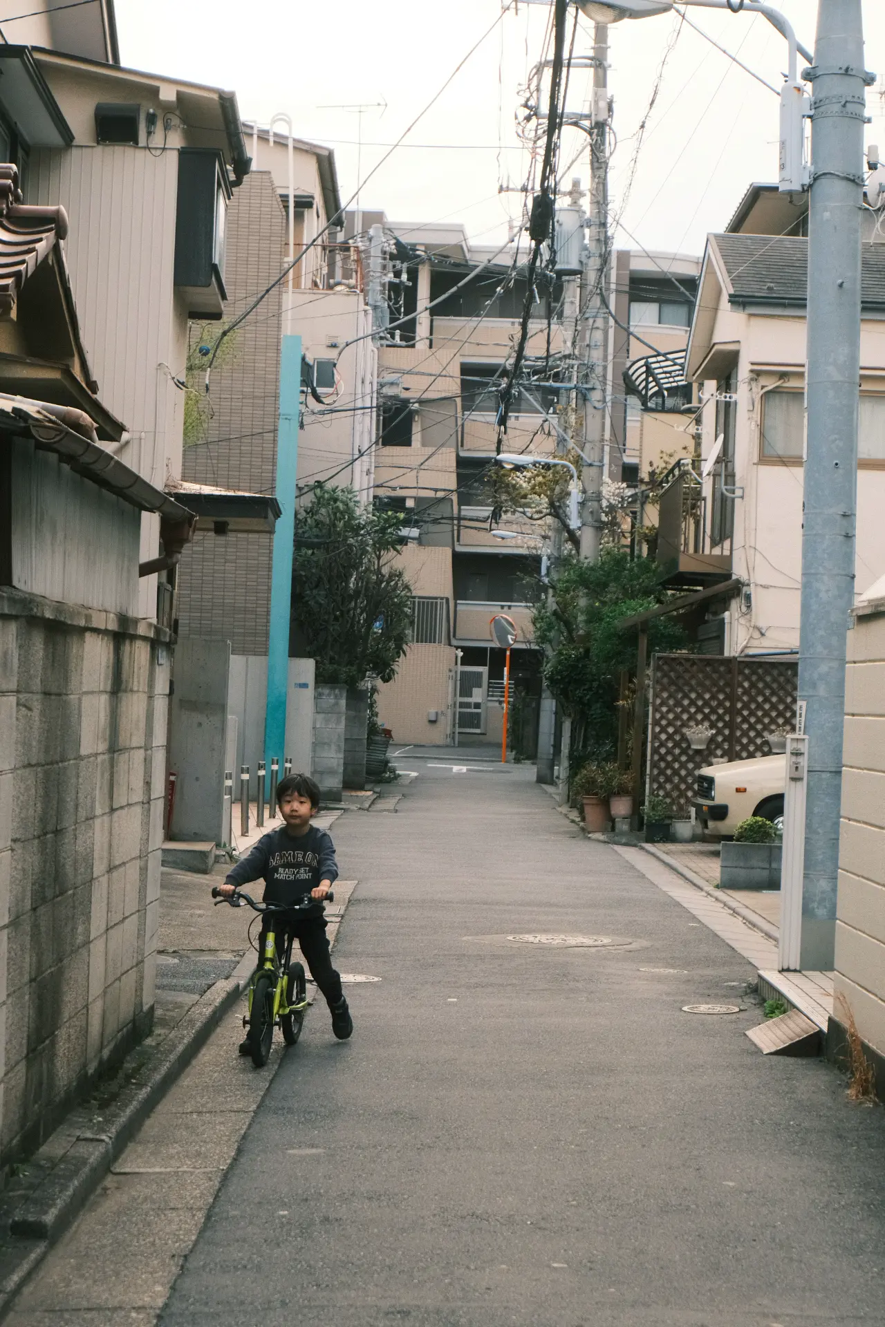 Un bambino in bicicletta in un vicolo residenziale giapponese