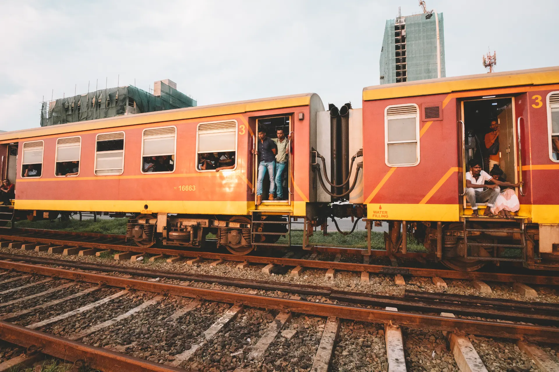 Il treno rosso e giallo dello Sri Lanka con la gente affacciata alle porte