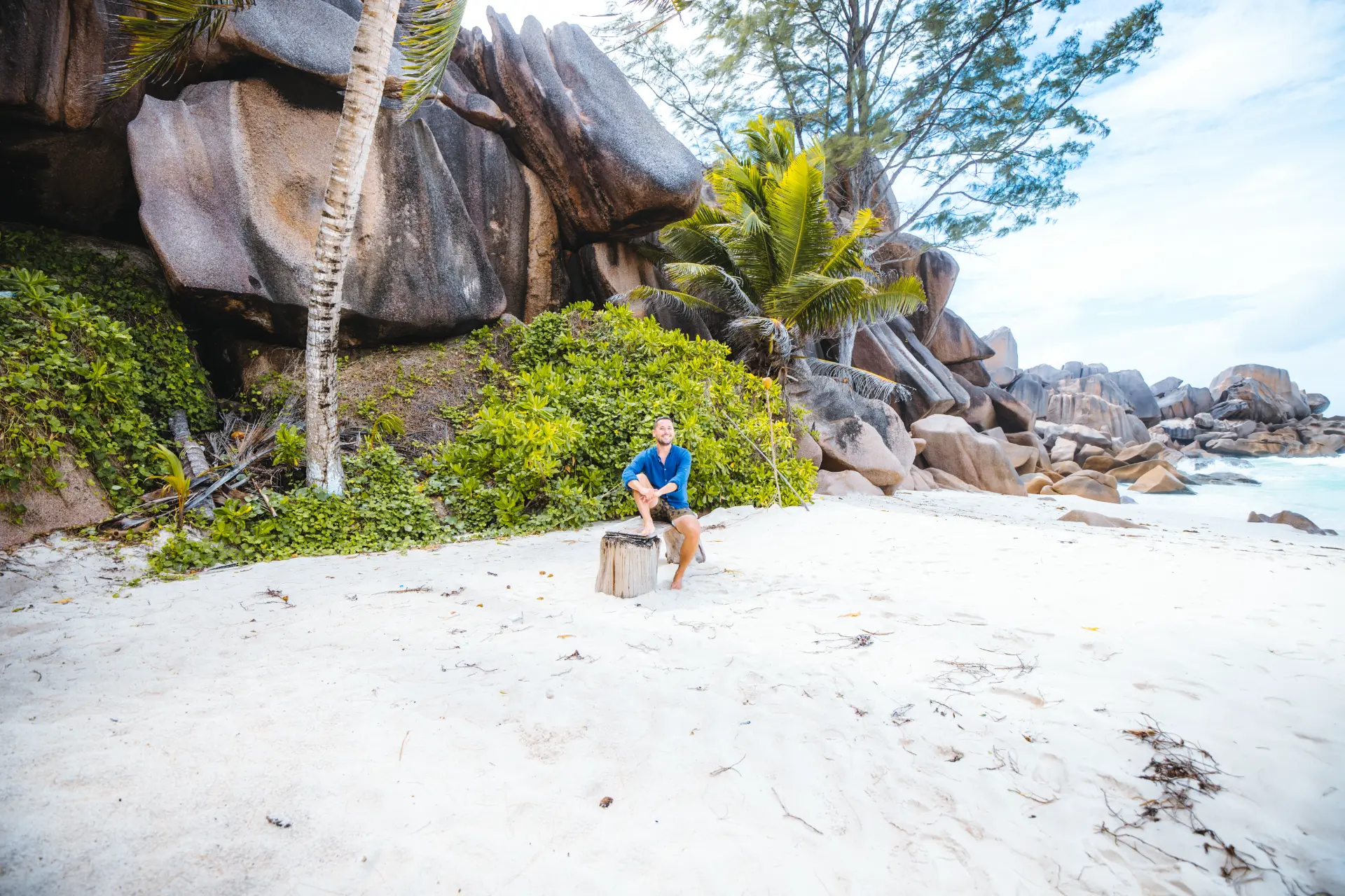 Io seduto su un ceppo tra i massi di granito di La Digue