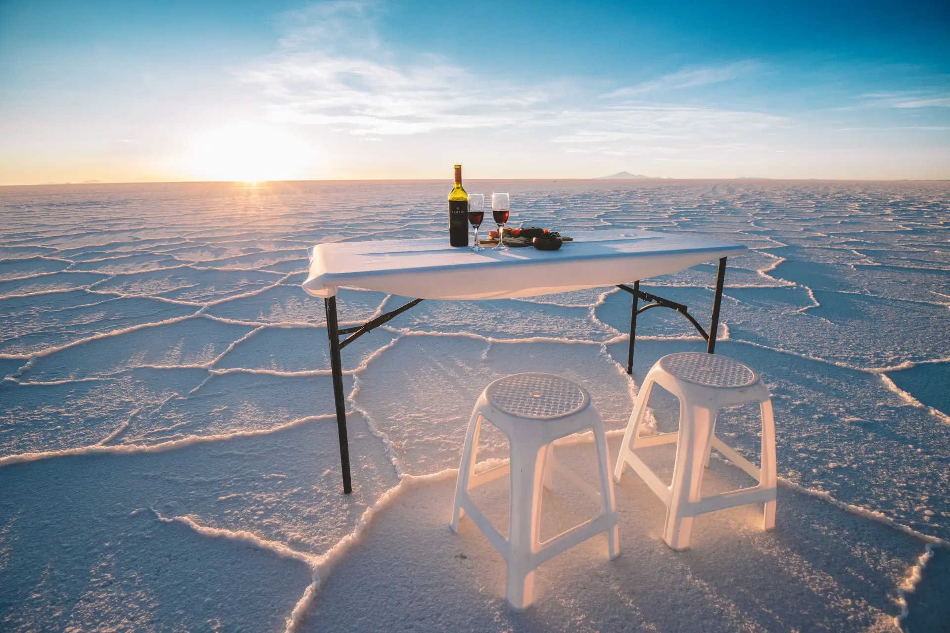 Aperitivo al tramonto con vino e tavolino sul Salar de Uyuni